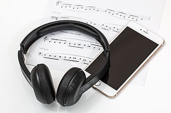 Black headphones and smartphone on sheet music
