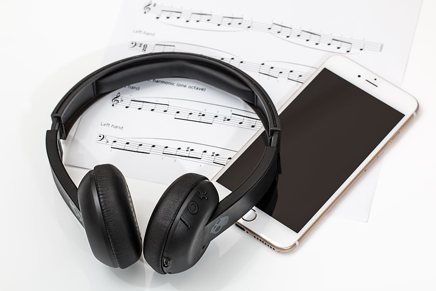 Black headphones and smartphone on sheet music