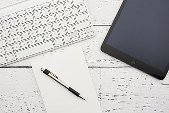 Top view of white workspace with keyboard, tablet, and pen