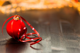 Red Christmas Ornament with Ribbon on Wooden Table