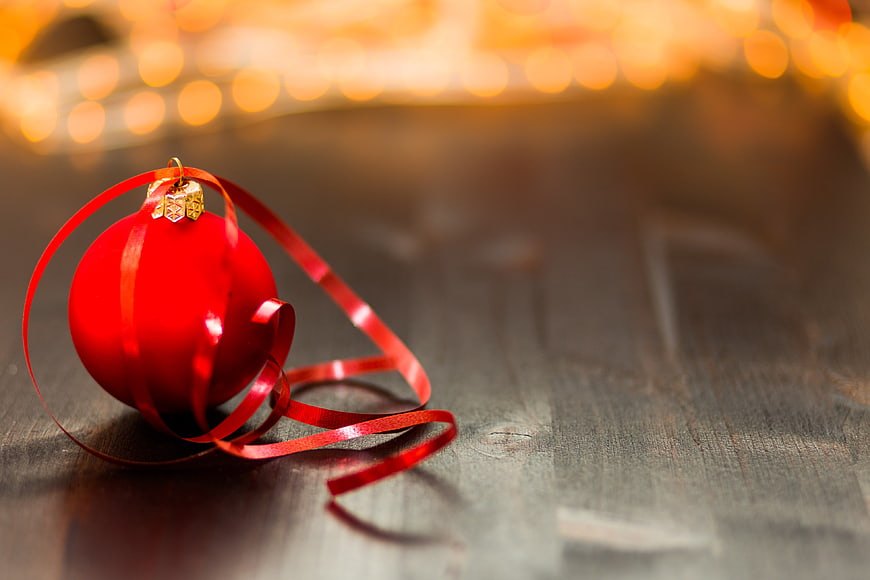 Red Christmas Ornament with Ribbon on Wooden Table