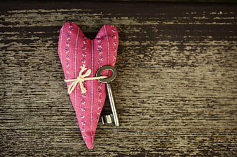 Vintage Key Tied to Pink Heart Sachet on Rustic Wood
