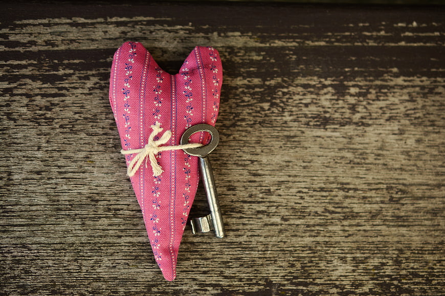 Vintage Key Tied to Pink Heart Sachet on Rustic Wood