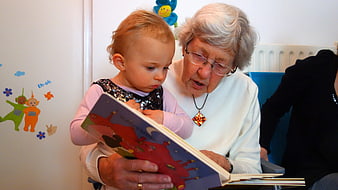 Grandmother reading a colorful picture book to a young toddler girl