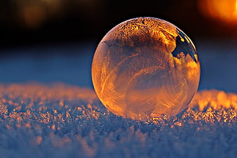 Frozen Ice Sphere on Frosty Ground at Sunset