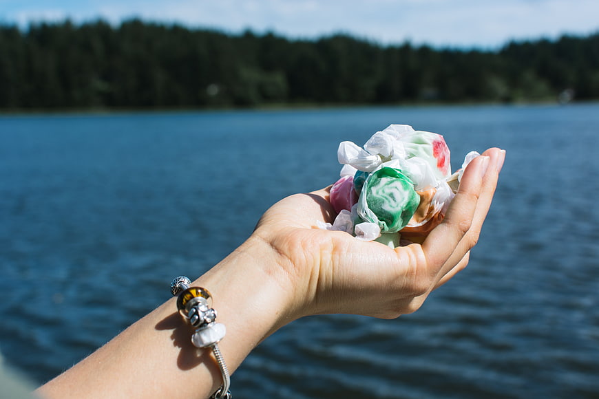 Hand holding colorful salt water taffy by lake