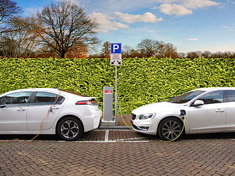 Two white electric cars charging at outdoor station