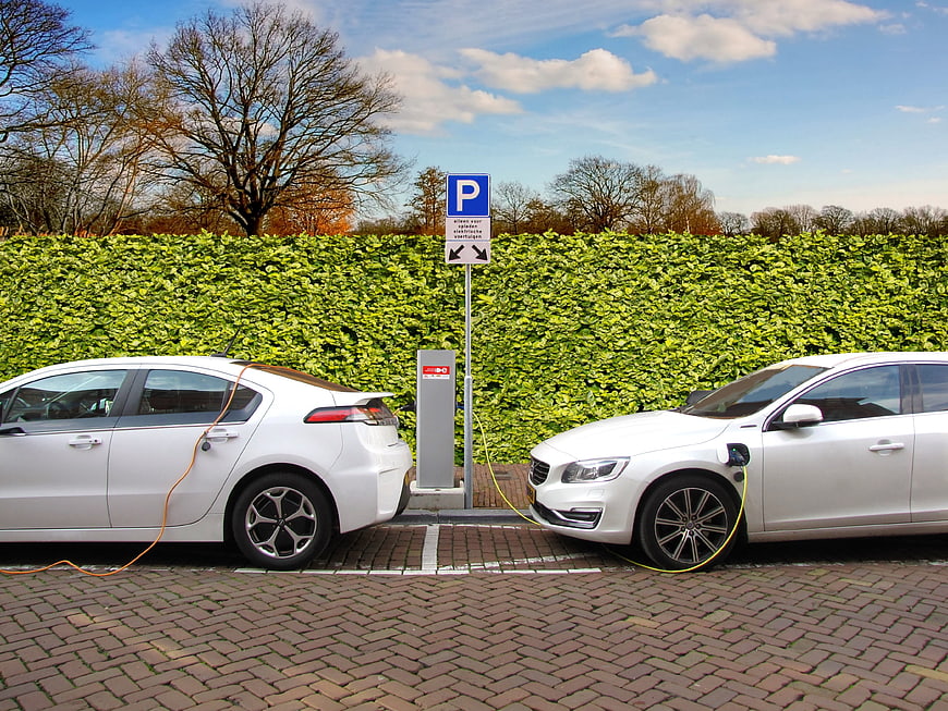 Two white electric cars charging at outdoor station