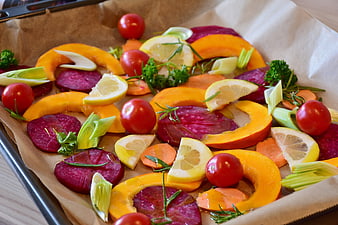 Raw autumn vegetables on baking sheet with lemon and herbs