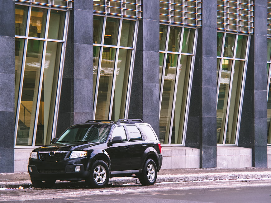 Black SUV Parked in Front of Modern Glass Building