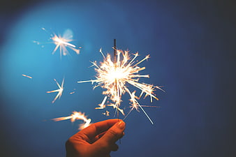 Hand Holding Sparkler Against Blue Twilight Sky