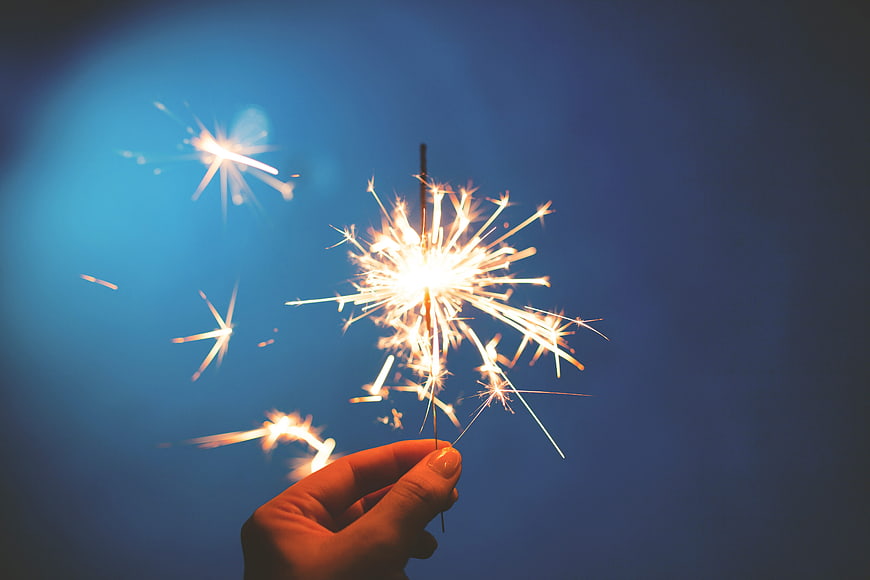 Hand Holding Sparkler Against Blue Twilight Sky