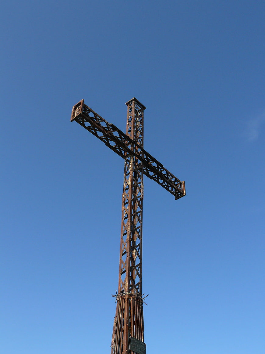 Rusty metal cross against clear blue sky