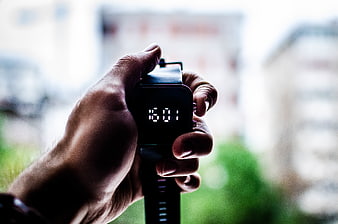 Hand holding digital watch showing 16:01