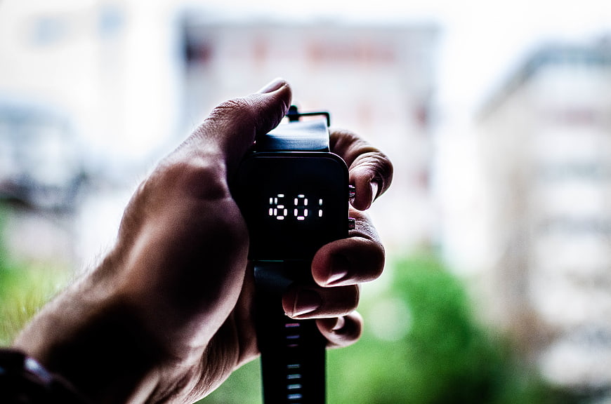 Hand holding digital watch showing 16:01