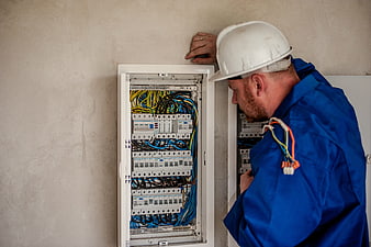 Electrician inspecting open electrical panel with wires