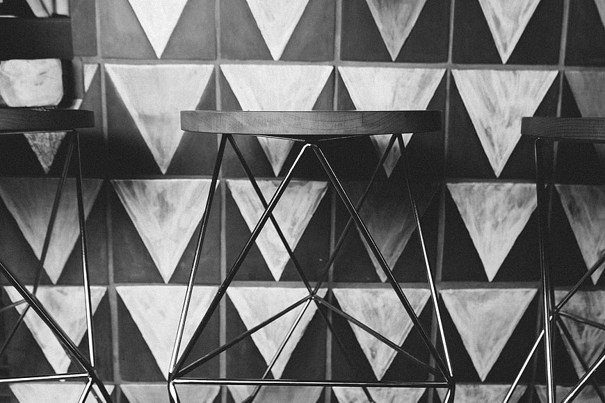 Black and white geometric stools against triangular tile wall