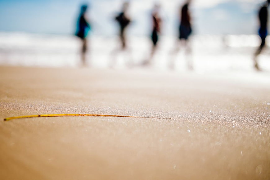 Close-up of Sand Texture with Blurred People on Beach