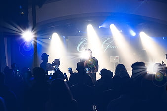 Silhouetted crowd recording live concert performance on stage