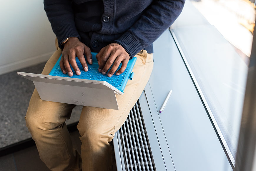 Man typing on blue laptop keyboard in office