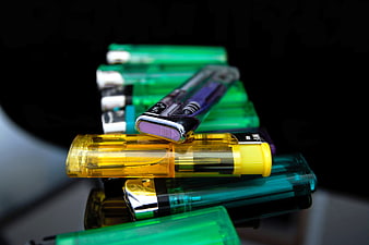 Stack of colorful disposable lighters on black background