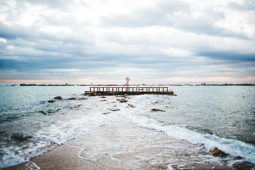 Serene coastal pier with gentle waves and overcast sky