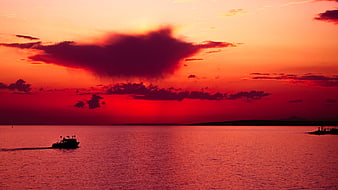 Silhouette of boat on sea during dramatic red sunset