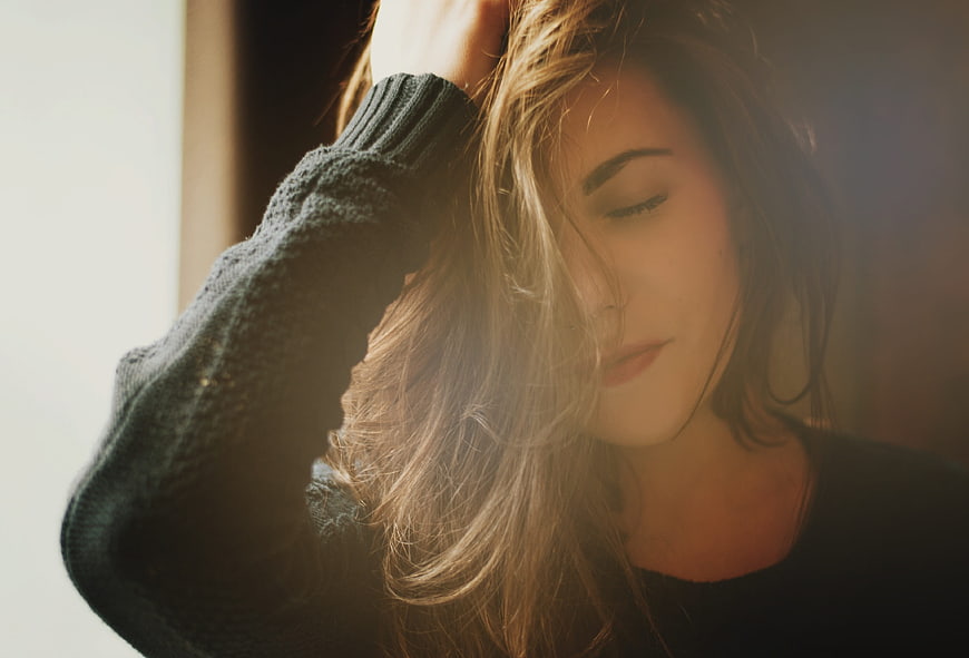 Woman with eyes closed in warm morning light