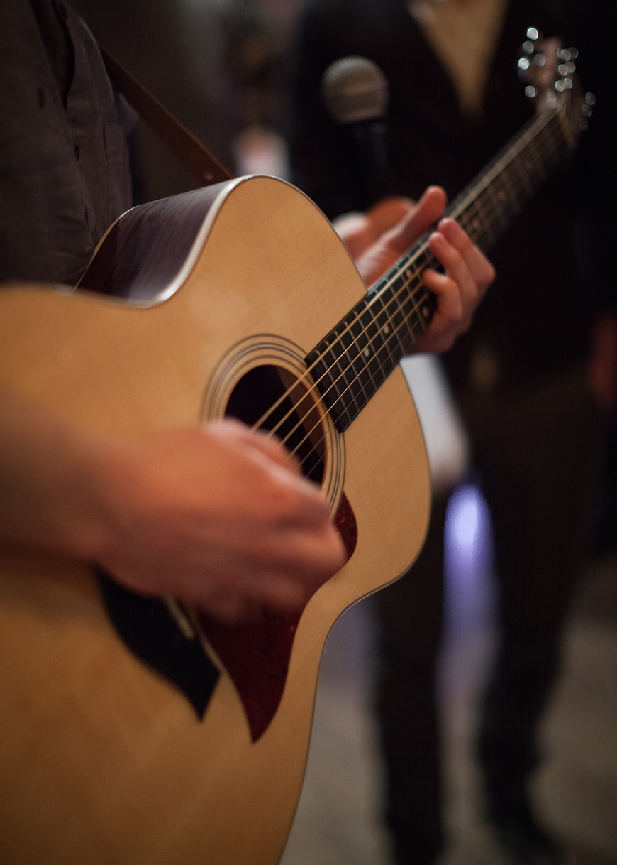 Close-up of hands playing acoustic guitar on stage