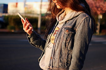 Young Woman Using Smartphone in Denim Jacket Outdoors