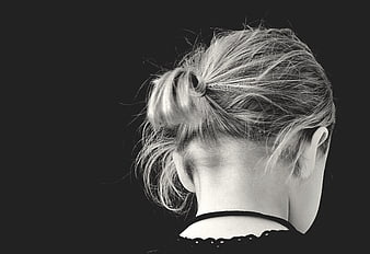 Black and white portrait of a young girl with a messy bun from behind