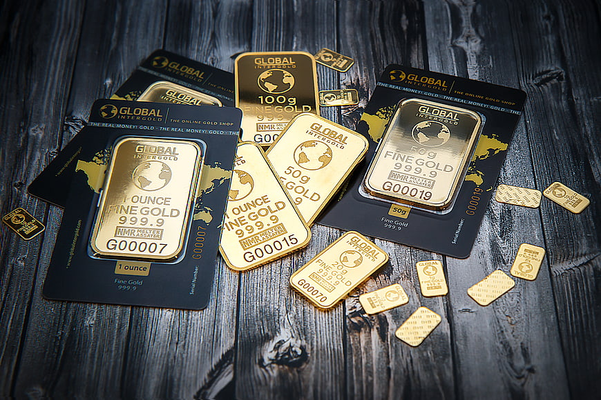 Collection of gold bars and coins on dark wood