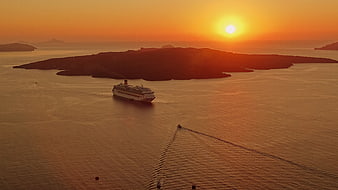 Cruise ship sailing past island at golden sunset