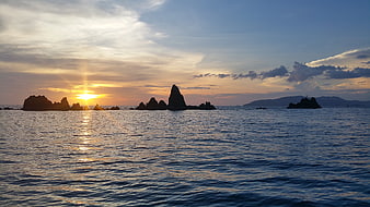 Sunset over ocean with silhouetted rock formations