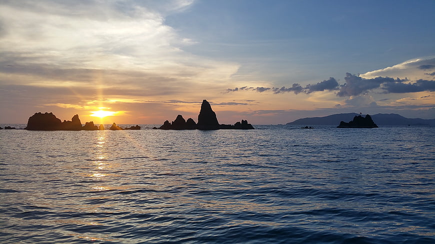 Sunset over ocean with silhouetted rock formations
