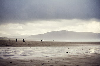 Moody Beach Landscape with Distant Mountains and Walking Figures