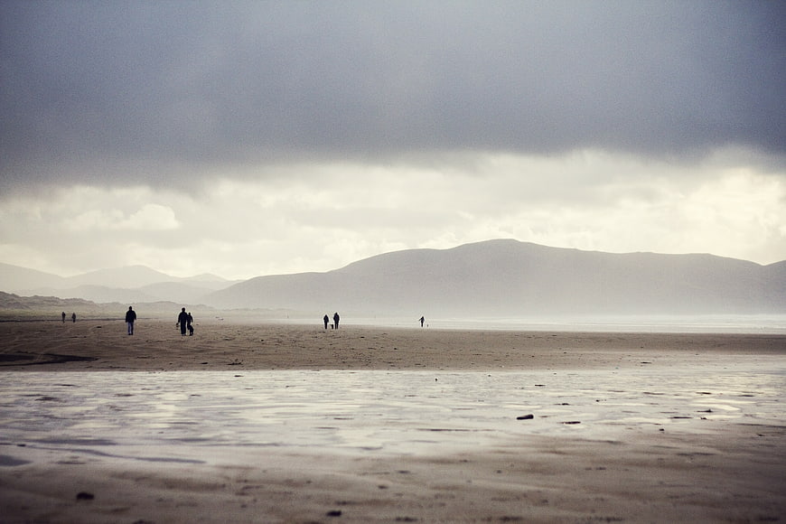 Moody Beach Landscape with Distant Mountains and Walking Figures