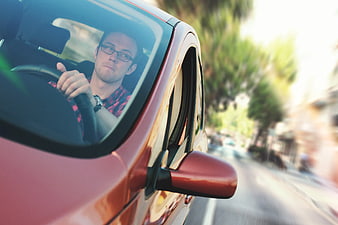 Man Driving Red Car on Sunny Street