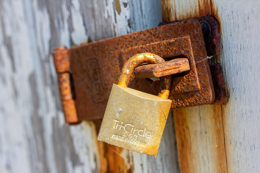 Rusty padlock on weathered wooden door