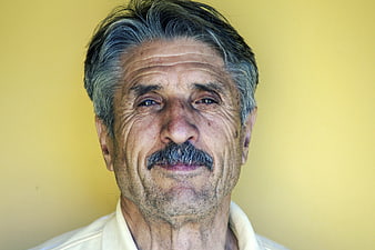 Portrait of elderly man with mustache against yellow background