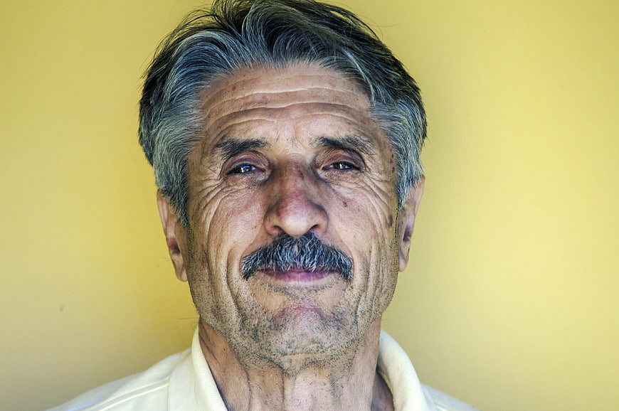 Portrait of elderly man with mustache against yellow background