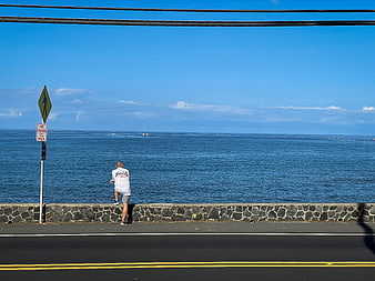 Man Stretching on Coastal Road Overlooking Blue Ocean