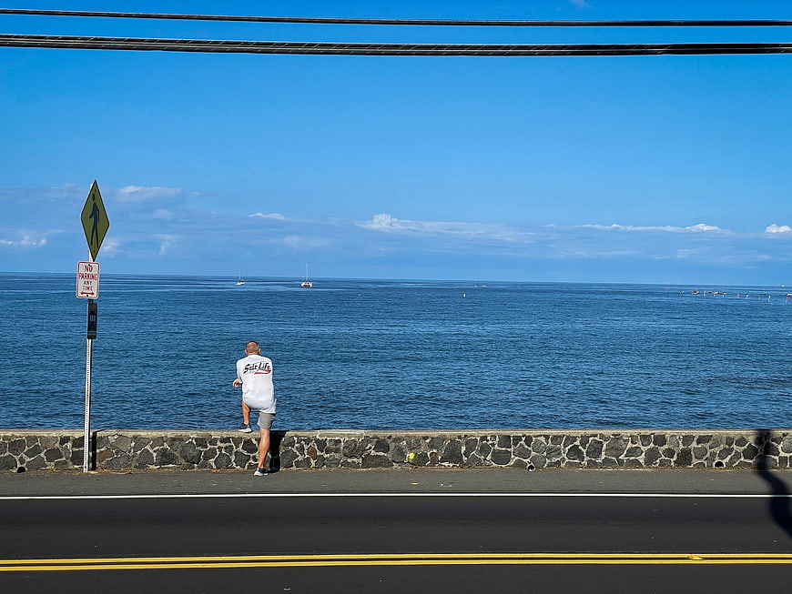 Man Stretching on Coastal Road Overlooking Blue Ocean