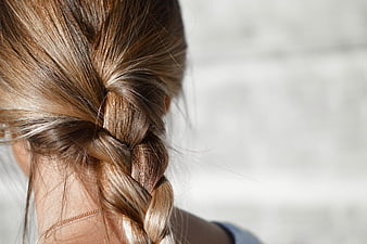 Close-up of a woman's blonde braided hair against a blurred background