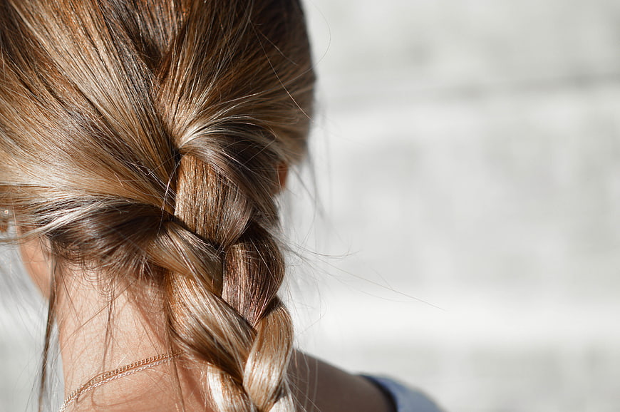 Close-up of a woman's blonde braided hair against a blurred background