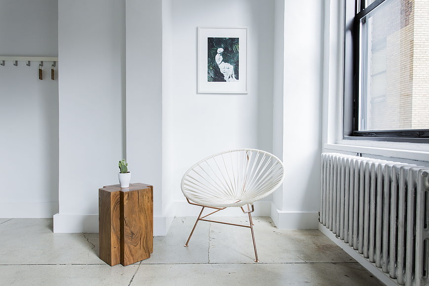 Modern white interior with Acapulco chair and wooden side table