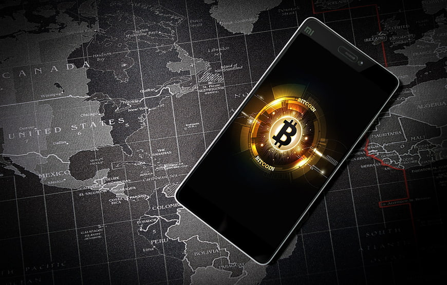 Smartphone displaying Bitcoin logo on dark world map background