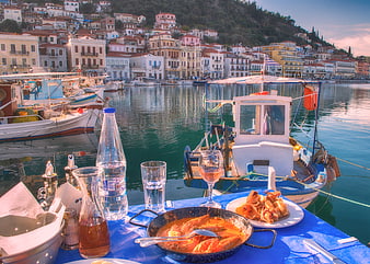 Seafood dinner on boat in Greek harbor with village background