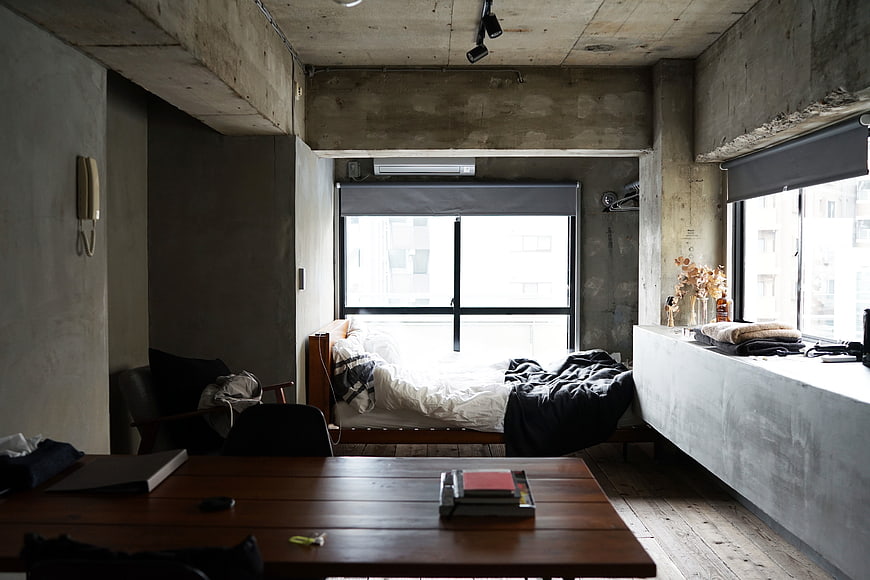 Industrial loft bedroom with concrete walls and wooden furniture