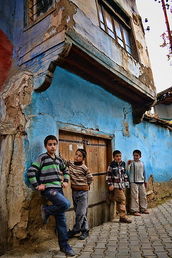 Four young boys standing in front of a weathered blue building